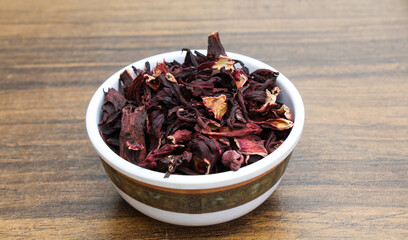 Dried Hibiscus flowers in a bowl on wooden background 