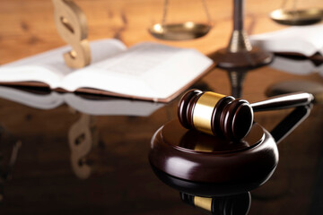 Law concept. Judge’s gavel legal books on the brown shining desk. Brown wooden background.