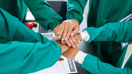 Multiracial medical team having a meeting with doctors in white lab coats and surgical scrubs seated at a table discussing a patients records