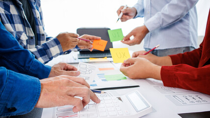 Close-up ux developers and ui designers use augmented reality to brainstorm on mobile app interface wireframe designs on modern office desks. Creative digital development office