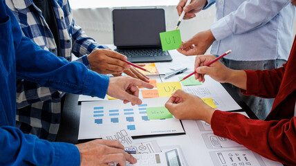 Close-up ux developers and ui designers use augmented reality to brainstorm on mobile app interface wireframe designs on modern office desks. Creative digital development office