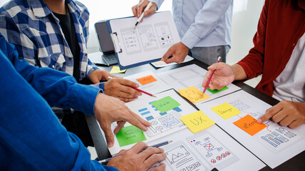 Close-up ux developers and ui designers use augmented reality to brainstorm on mobile app interface wireframe designs on modern office desks. Creative digital development office