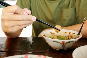 Image of a person sitting eating noodles