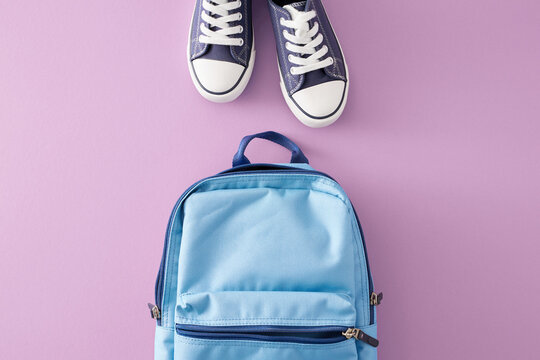 The concept of stylish things for the beginning of the school year. Top view composition of blue schoolbag, modern footwear on pastel purple background