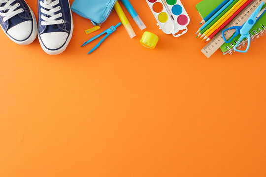 Ready for the academic season ahead. Top view photo of assorted colorful school tools, stylish sneakers on orange background with empty space for advert or text