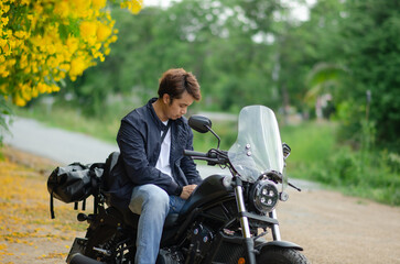 asian young man is sitting on cruiser motorcycle with yellow tre