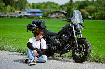 asian young man is sitting on road with cruiser motorcycle and g
