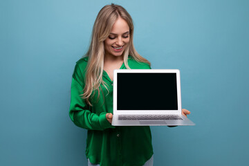 a cute girl demonstrates a laptop with a screen to insert a page on a blue bright background