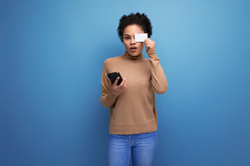 Fototapeta premium isolated with background, well groomed pretty young brunette hispanic woman with ponytail hairstyle holding credit card and phone