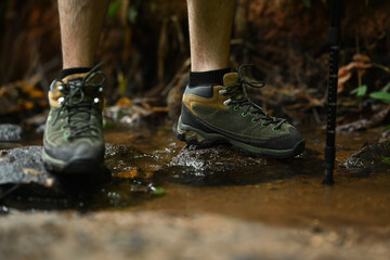 Male hiker crossing the forest creek. Travel, summer vacations adventure and active life concept.