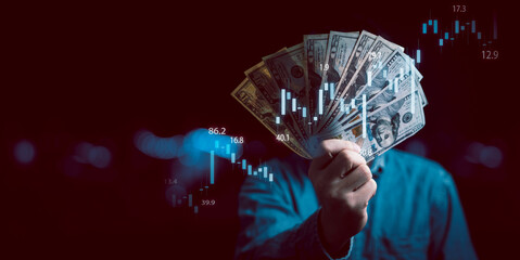 Businessman holding dollar banknote with stock market graph and up arrow for inflation and interest...