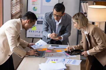 Group of confident business people point to graphs and charts to analyze market data, balance sheet, account, net profit to plan new sales strategies to increase production capacity.	