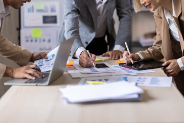 Fototapeta premium Group of confident business people point to graphs and charts to analyze market data, balance sheet, account, net profit to plan new sales strategies to increase production capacity. 