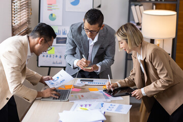 Group of confident business people point to graphs and charts to analyze market data, balance sheet, account, net profit to plan new sales strategies to increase production capacity.	