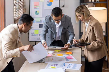 Group of confident business people point to graphs and charts to analyze market data, balance sheet, account, net profit to plan new sales strategies to increase production capacity.	