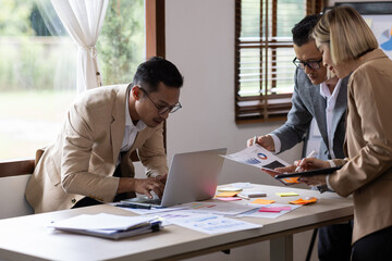 Group of confident business people point to graphs and charts to analyze market data, balance sheet, account, net profit to plan new sales strategies to increase production capacity.	