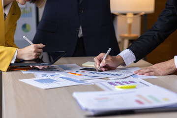 Group of confident business people point to graphs and charts to analyze market data, balance sheet, account, net profit to plan new sales strategies to increase production capacity.	