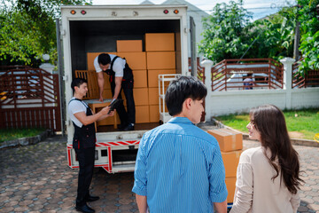 Asian Couple check while unloading boxes and furniture from a pickup truck to a new house with service cargo two men movers worker in uniform lifting boxes. concept of Home moving and delivery.