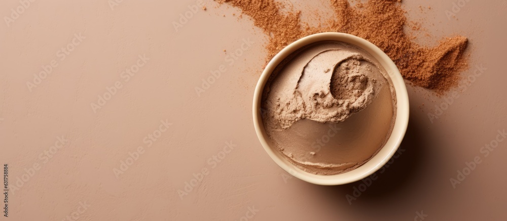 Sticker clay mask in a bowl for facial spa is placed on a beige background with a top view and copy space.