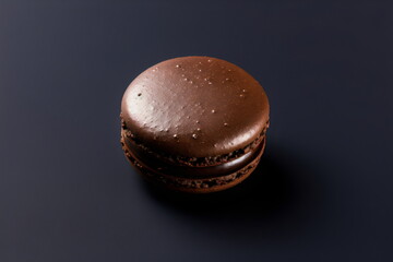 one chocolate macaron isolated on plain dark gray studio background