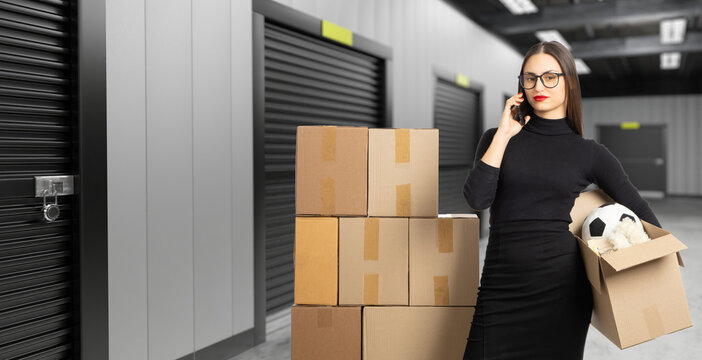 Woman near storage room. Businesswoman speaks on phone. Girl brought boxes to warehouse. Lady near closed storage room. Woman rents warehouse space. Storage room for personal items. Unit, container