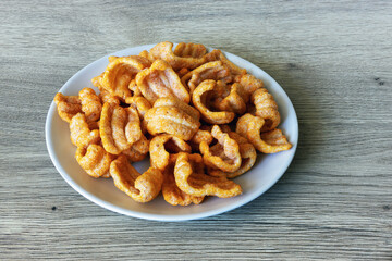 Ham-flavored crisp snacks on a plate on an oak table