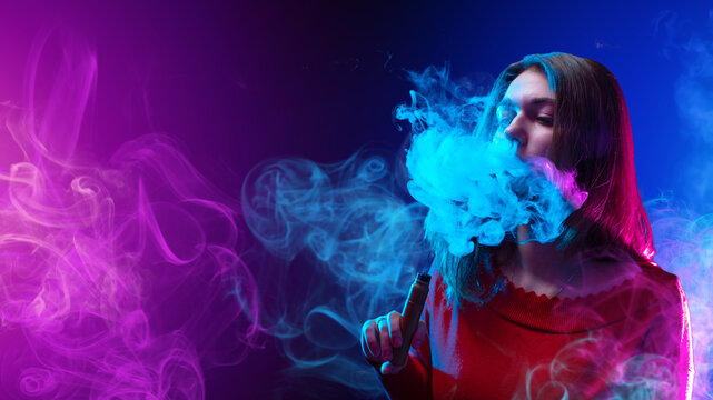 Woman vaper. Girl with electronic cigarette. Young woman smokes vape. Vaper blows smoke from nose. Girl with vaping device. Young lady vaper on purple. Vaping hobby. Vape as alternative to tobacco