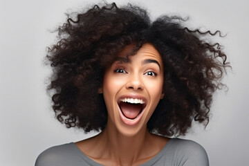 Positive human facial expressions, emotions, reaction and feelings, Attractive young dark skinned female with voluminous hairstyle laughing at joke, looking away, showing white perfect teeth
