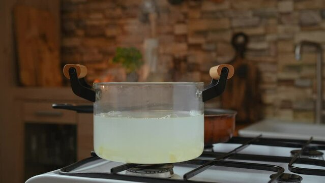 Broth in transparent glass saucepan on a gas stove
