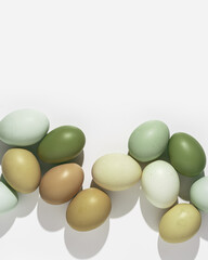 Natural colorful Easter eggs green beige yellow color on white light background, hard Shadow at sunlight. Minimal flat lay frame from Chicken eggs, traditional Easter holiday food, top view