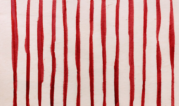 immagine primo piano di spesse righe verticali irregolari in inchiostro rosso su carta ruvida, vista dall'alto