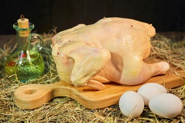 Raw chicken meat lies on a wooden chopping board. Raw eggs are lying nearby. Raw food for cooking.