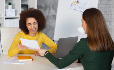 Recruitment manager talking, hiring for job new employee sitting in office. Caucasian female person having a job interview with African American woman recruiter