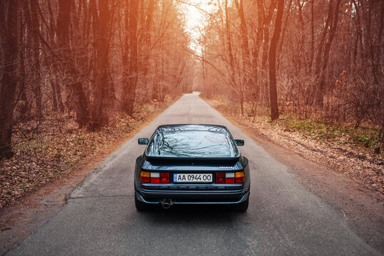 Racing video game but in real life - dark blue Porsche 944 on narrow road through a forest. I liked playing NFS when was a kid, now recreating moments in full scale. Kyiv, Ukraine - November 26 2017.