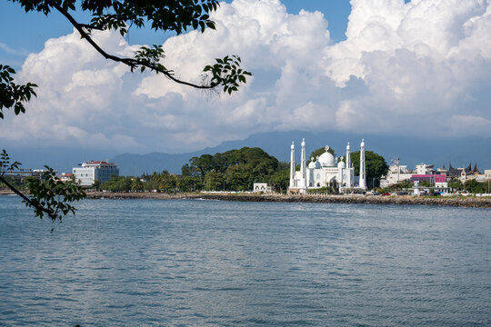 the view at al-hakim mosque is a mosque with beautiful architecture, the mosque is located on the seashore with a beautiful white cloud background