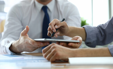Close-up of workers discussing new start-up. Customer signing electronic document in office. Man pointing with stylus on laptop. Business company and innovation concept