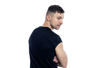 A handsome brutal man in a black T-shirt looks over his shoulder. Isolated on a white background.