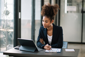 Young beautiful woman typing on tablet and laptop while sitting at the working  table office