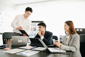 Group of young Asian business people discussing business plan at modern startup in creative business discussing work  office