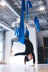 Woman practices aerial yoga pose in hammock