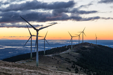 A group of wind power plants early in the morning while sunrise in Austria