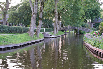 Water canal in the touristic village Giethoorn in the Netherlands, with its characteristic wooden bridges that connects all the separated areas. Photo made in the summertime.