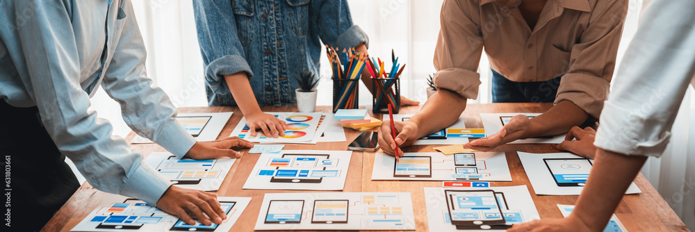 Poster Panorama shot of front-end developer team brainstorming UI and UX designs for mobile app on paper wireframe interface. User interface development team planning for user-friendly UI design. Scrutinize
