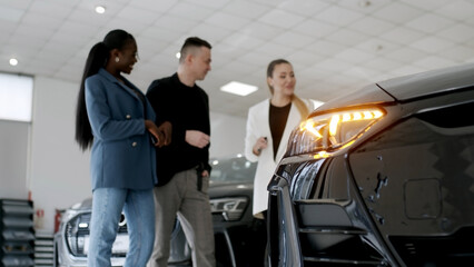 Car showroom. The manager shows the car to buyers in the showroom. copy space