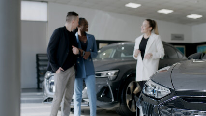 Fototapeta na wymiar Car showroom. The manager shows the car to buyers in the showroom. copy space