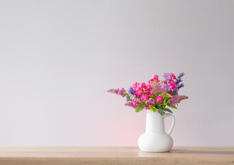beautiful flowers in white jug on wooden shelf