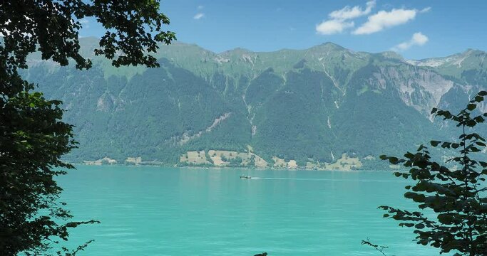 Lake Brienz in Swiss Alps. The trail between Iseltwald and Giessbach along a beautiful shoreline with view on motorboats crossing the beautiful calm turquoise waters of the lake