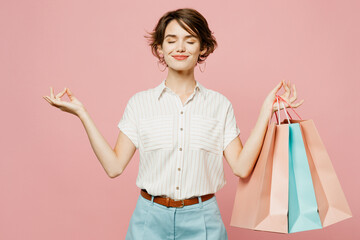 Young woman wear casual clothes hold shopping paper package bags spread hands in yoga om aum...