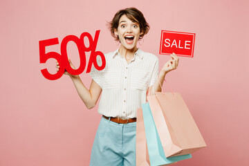 Young surprised shocked woman wear casual clothes hold shopping paper package bags sale written...