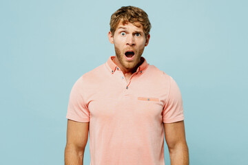Young shocked surprised caucasian blond man wear pink t-shirt casual clothes look camera with...